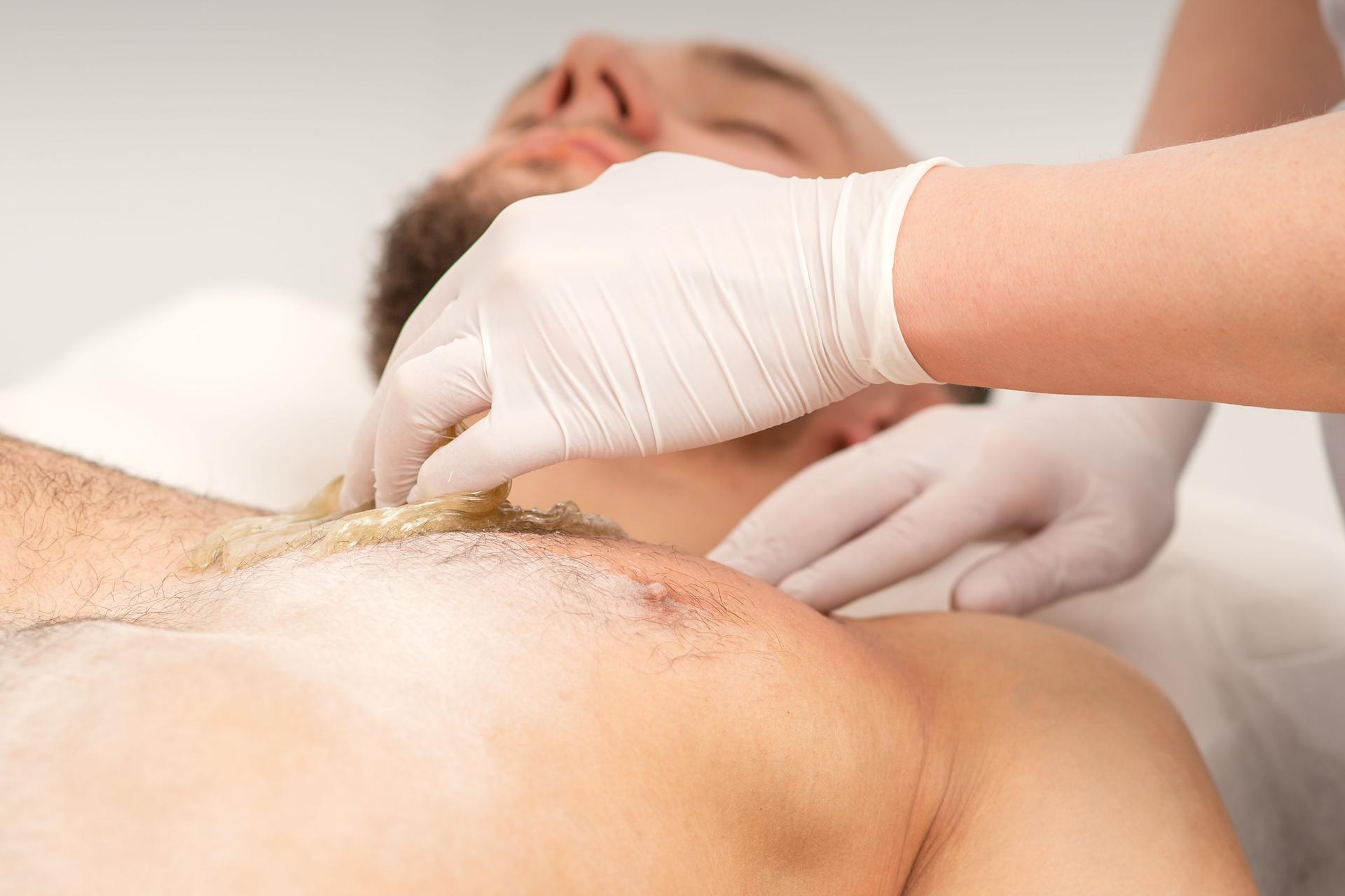 Epilation chest of a young male with the liquid wax paste in a beauty salon.