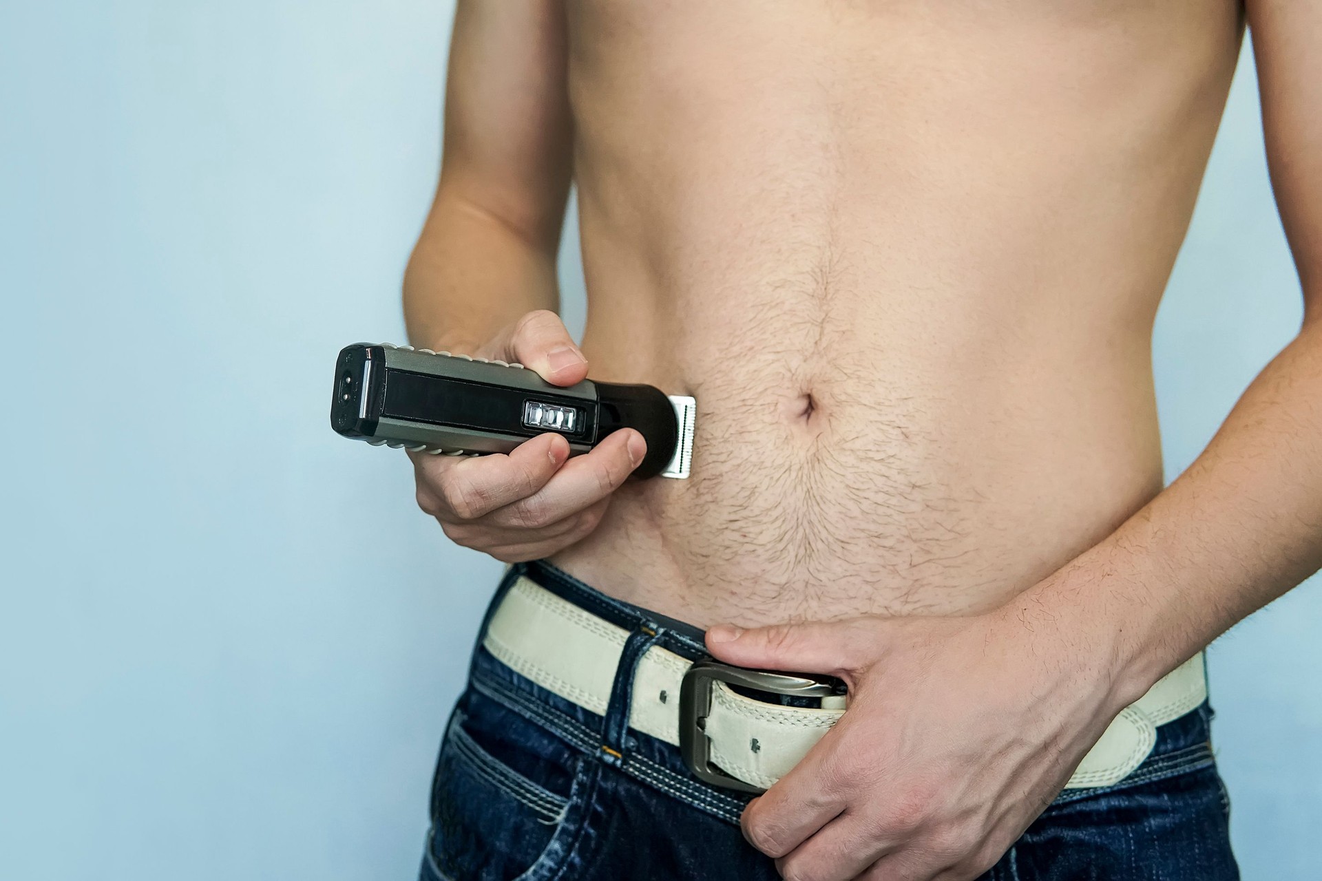 closeup of a young man trimming the hair of his pubis with an electric trimmer. concept of a clean healthy body for men. Man haircut pubic hair with a clipper.
